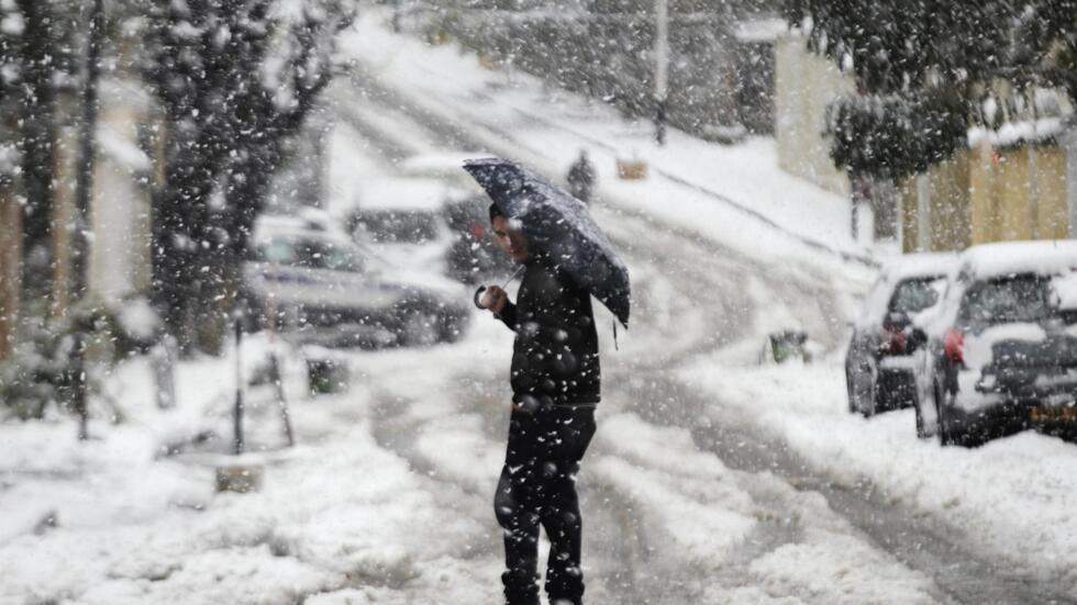 A man walks under an umbrella during snowfall in Algiers Chutes de Neige Imminentes sur 13 Wilayas Algériennes à Partir de Lundi 23 Décembre